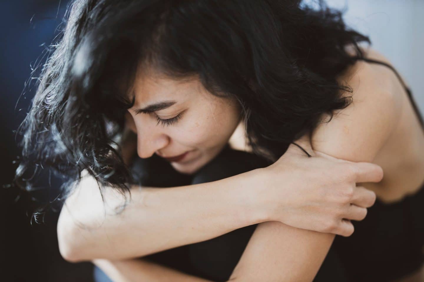 woman hugging knees looking stressed