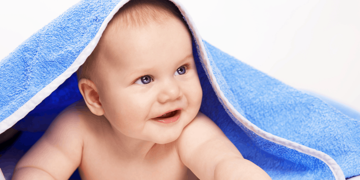 Baby has blue eyes and has a blue towel over his head