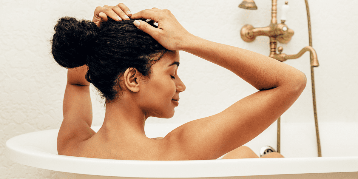 lady sitting in bath with her hands placed on her head. She looks relaxed