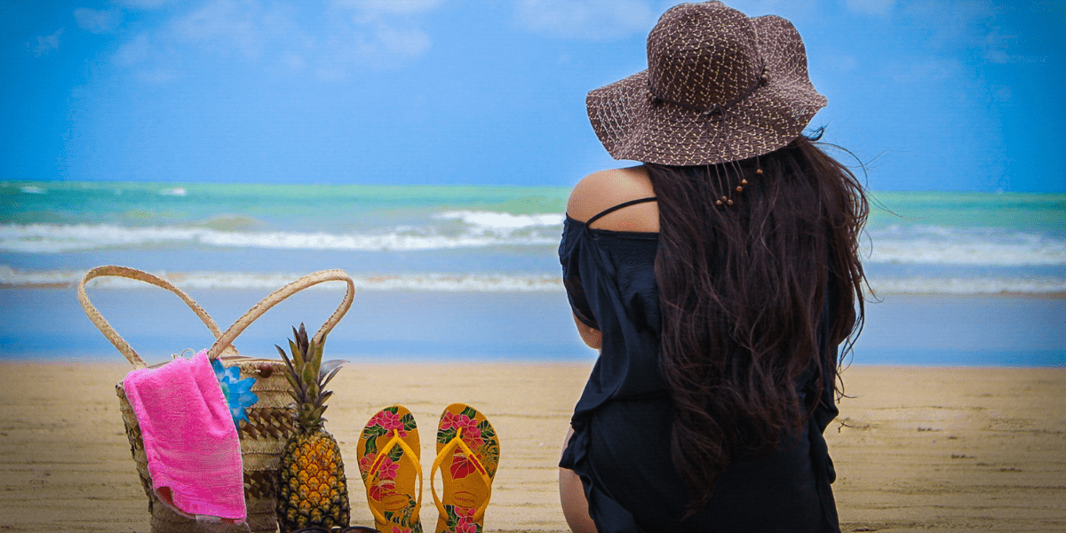 woman sitting on the beach next beach bag