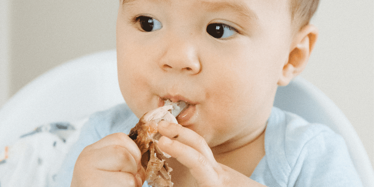 baby feeding himself food